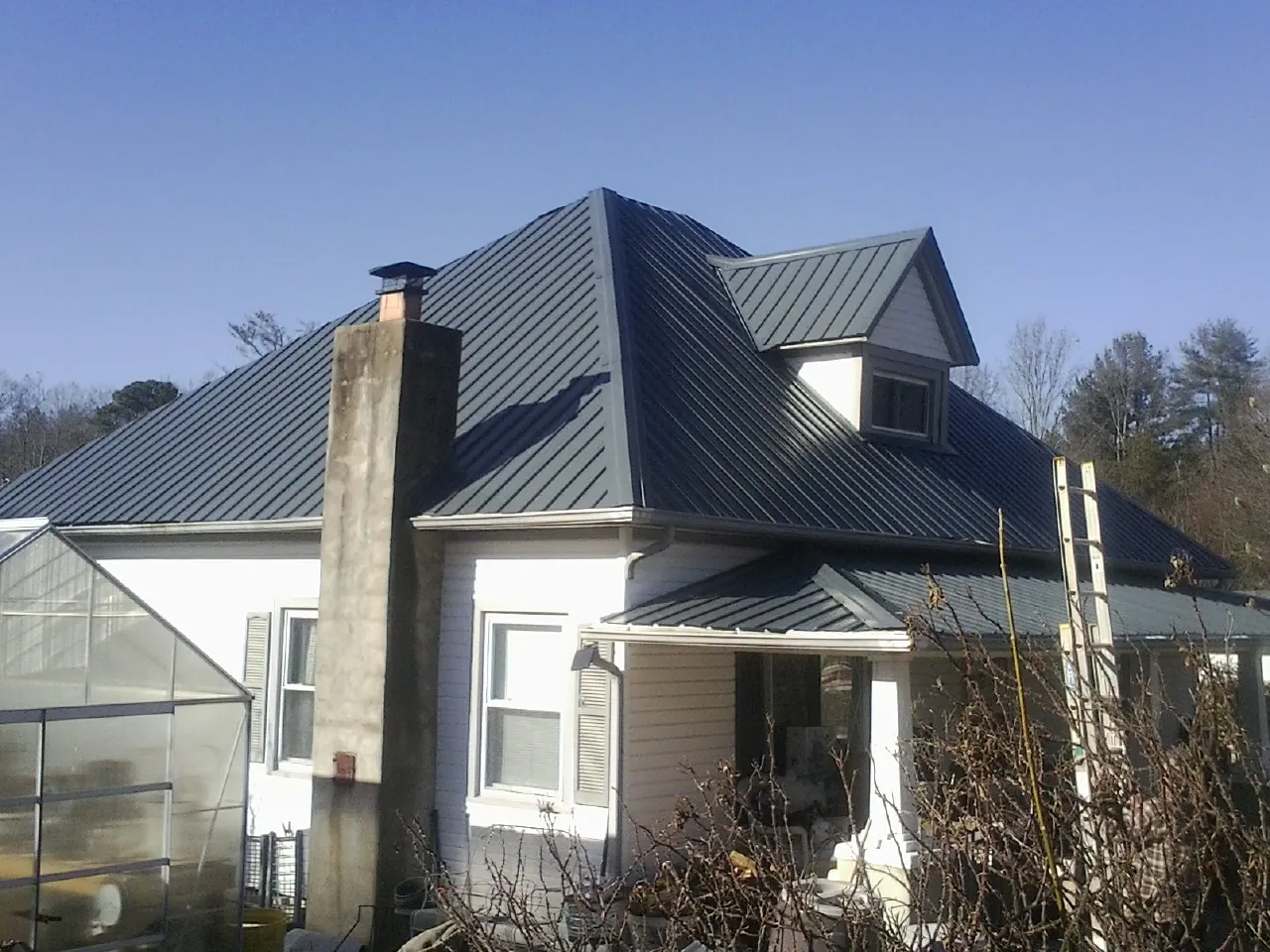 Dark blue standing seam metal roof on a white farmhouse with dormer — Slate & Tile Roof Repair by Roofing Brothers in Gilroy