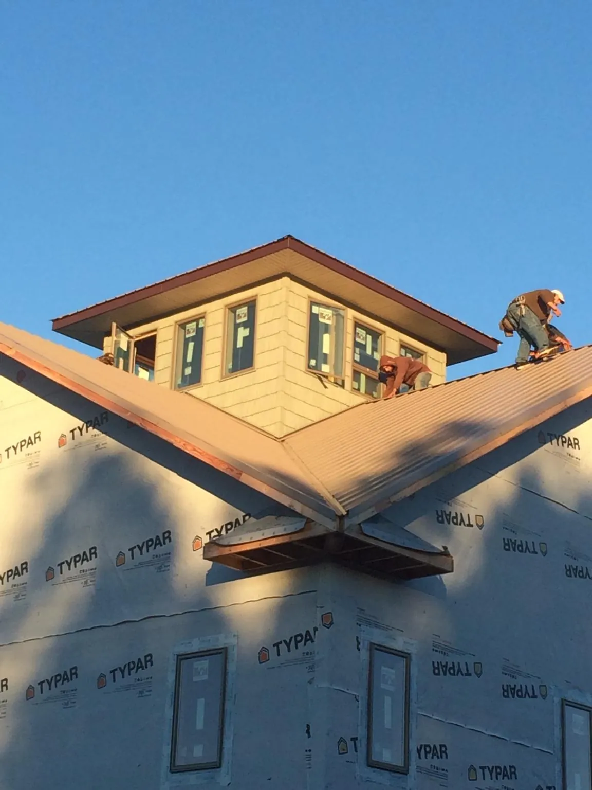 Roofers working around a rooftop cupola on a new metal roof at sunset — Roof Waterproofing in Gilroy by Roofing Brothers